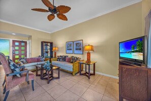 A living room with a sofa, armchairs, a coffee table, a television, and a ceiling fan. - Kapalua Ridge | 3 Ocean View Villas, Sleeps 16 | Car Incl. w/ 6+ Nights | ML-4256 by KBM (Lahaina)
