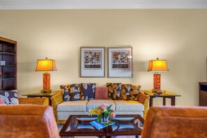 A living room with a sofa, two side tables with lamps, a bookshelf, and two framed pictures on the wall. - Kapalua Ridge | 3 Ocean View Villas, Sleeps 16 | Car Incl. w/ 6+ Nights | ML-4256 by KBM (Lahaina)