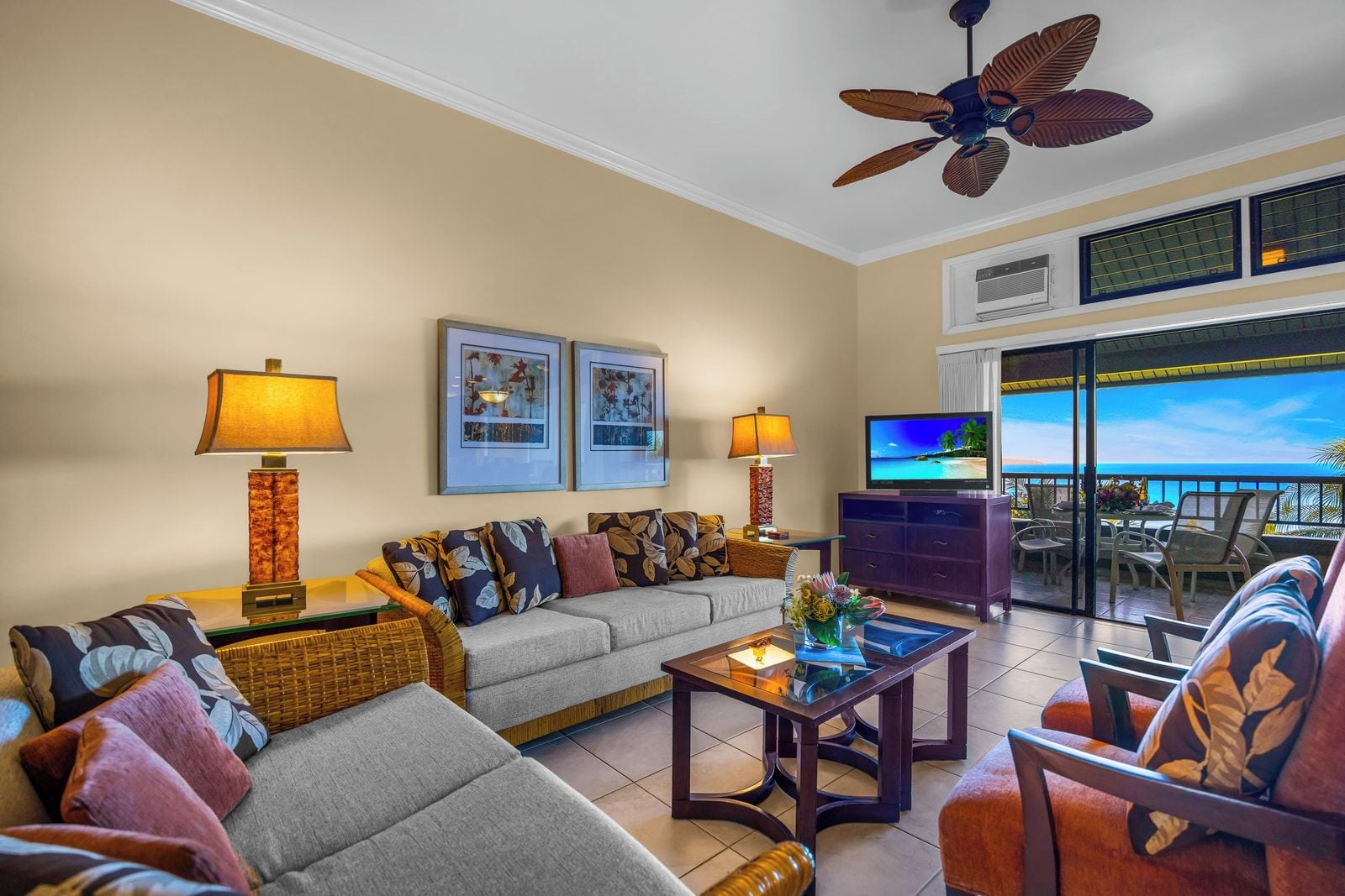 A living room with a sofa, two side tables with lamps, a television, and a balcony with a view.