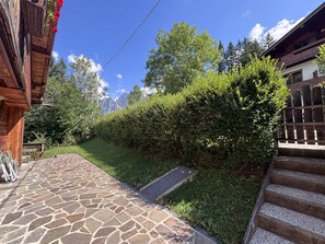 A stone pathway leading to a wooden building with a wooden fence and a grassy area. - Casa di Gio, close to the center with balcony and beautiful views (Cortina d´Ampezzo)