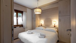 Ein Schlafzimmer mit einem großen Bett, zwei Nachttischlampen und einem Fenster mit Vorhängen.