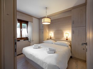 A bedroom with a large bed, two bedside lamps, and a window with curtains. - Casa di Gio, close to the center with balcony and beautiful views (Cortina d´Ampezzo)