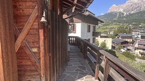 Ein Holzgebäude mit einer Steintreppe, die zu einem Balkon mit Blick auf eine Berglandschaft führt.