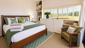 A bedroom with a bed, a chair, a window, and a shelf with plants. - Kapalua Ridge | 2 Ocean View Villas, Sleeps 8 | Car Incl. w/ 6+ Nights | ML-4259 by KBM (Lahaina)
