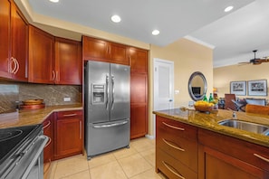 A kitchen with wooden cabinets, a stainless steel refrigerator, granite countertops, and a built-in oven. - Kapalua Ridge | 2 Ocean View Villas, Sleeps 8 | Car Incl. w/ 6+ Nights | ML-4259 by KBM (Lahaina)