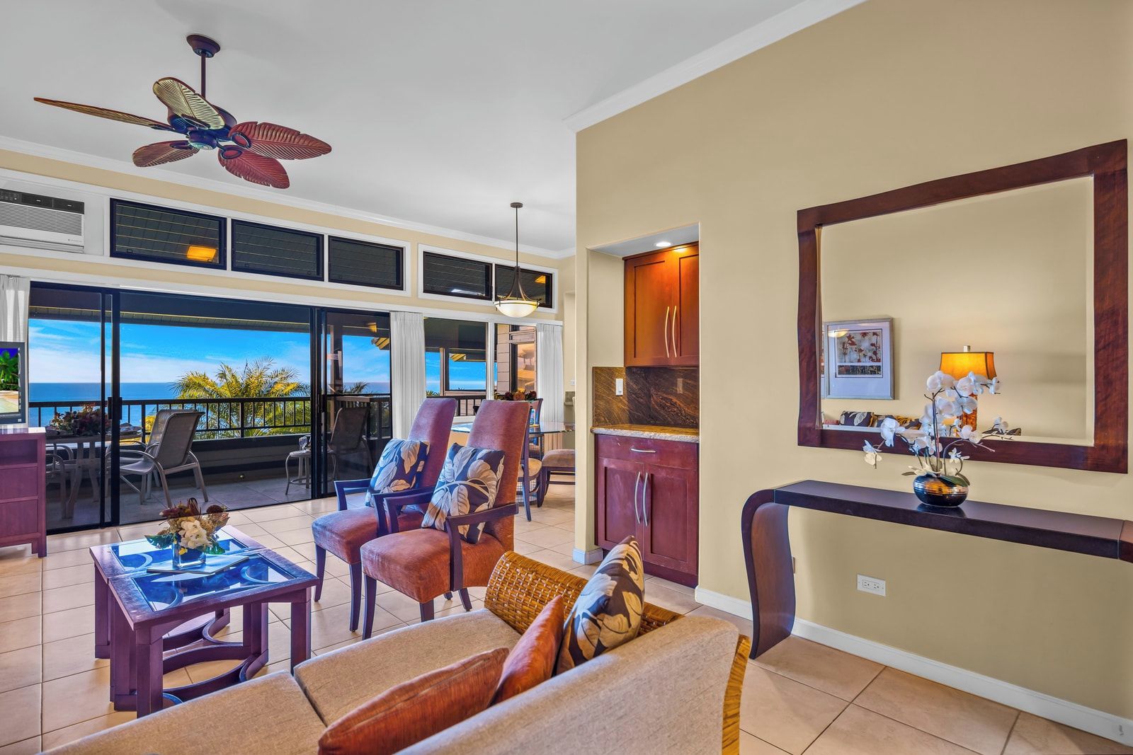 A spacious living area with a view of the ocean, a ceiling fan, and a dining area with a view.