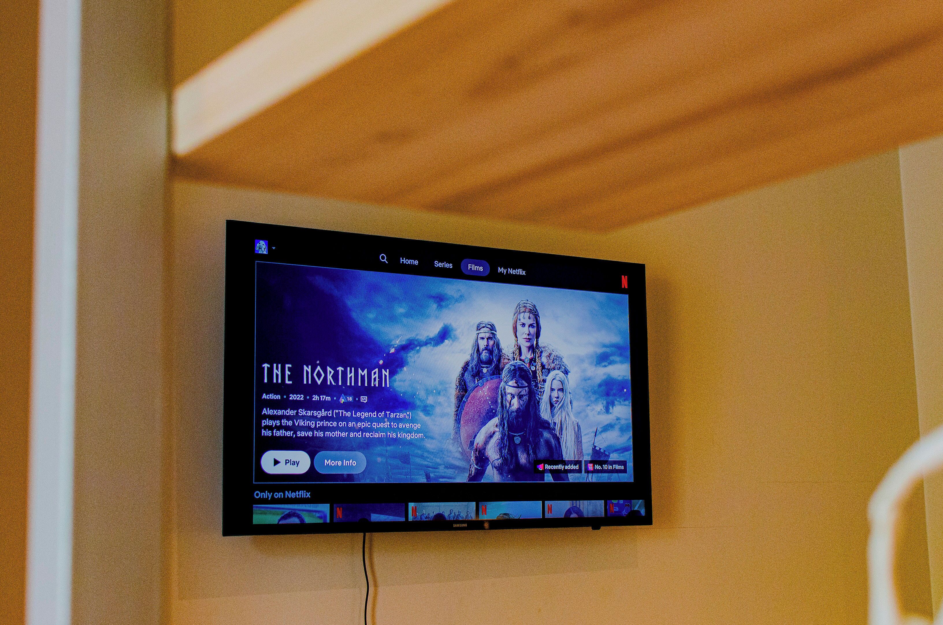 A television mounted on a wall displaying a movie poster for 'The Northman' on Netflix.