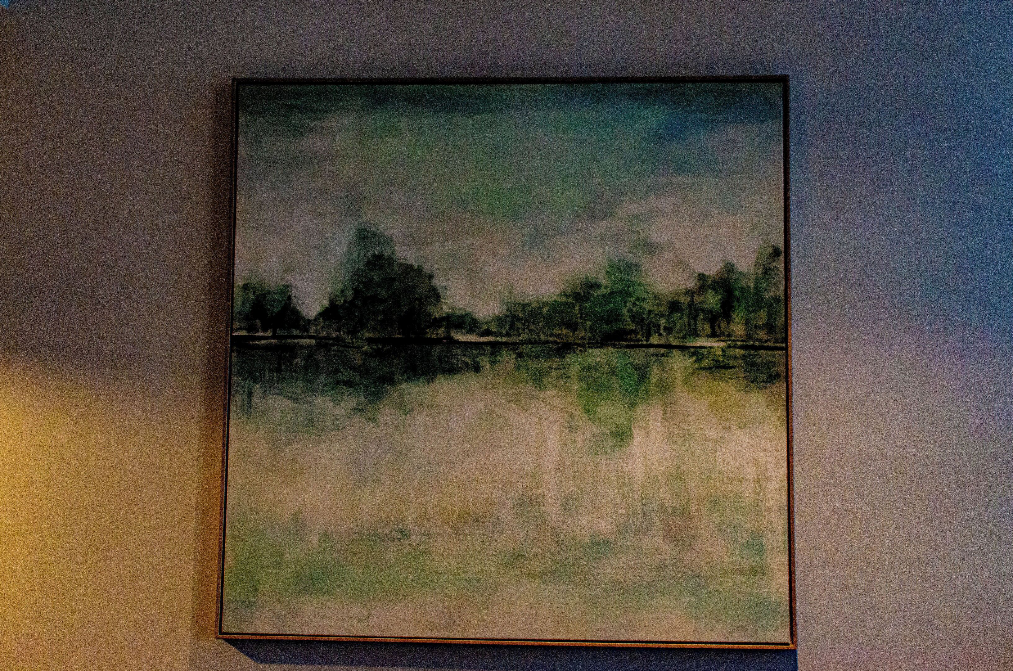 Pintura de paisaje enmarco con un reflejo en la pared.