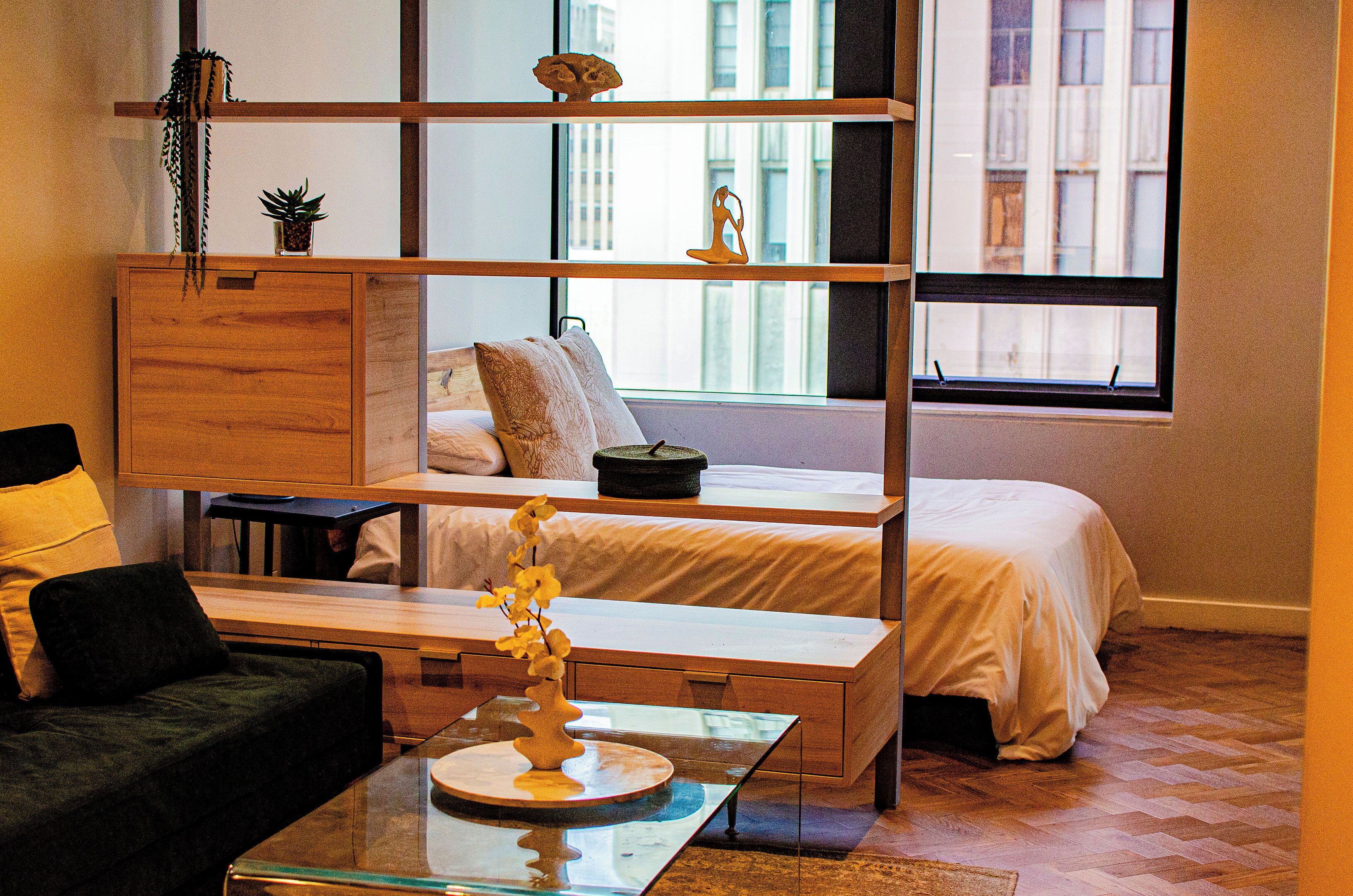 A modern bedroom with a bunk bed, a glass coffee table, and a view of the city through large windows.