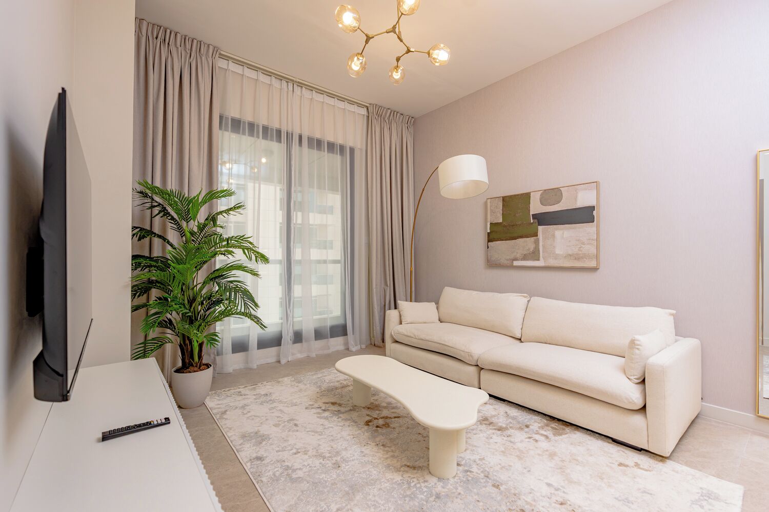 A modern living room with a sofa, a coffee table, a TV, a plant, and a painting on the wall.