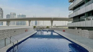 A rooftop swimming pool with a cityscape view, a covered walkway, and a modern building facade. - Partial marina view prime location (Dubai)