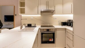 A modern kitchen with a built-in oven, a microwave, and a coffee maker on the countertop. - Partial marina view prime location (Dubai)