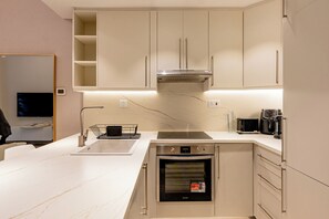 A modern kitchen with a built-in oven, a microwave, and a coffee maker on the countertop. - Partial marina view prime location (Dubai)