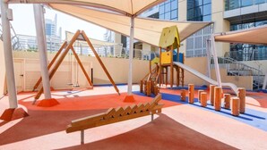 A children's play area with a slide, climbing structures, and a bench. - Partial marina view prime location (Dubai)