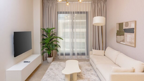 A modern living room with a flat-screen TV, a sofa, a coffee table, a potted plant, and a floor lamp. - Partial marina view prime location (Dubai)