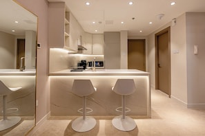 A modern kitchen with a marble countertop, two bar stools, and a built-in coffee machine. - Partial marina view prime location (Dubai)