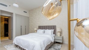 A modern bedroom with a large bed, bedside lamps, and a decorative floor lamp. - Partial marina view prime location (Dubai)