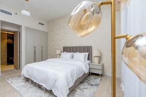 A modern bedroom with a large bed, bedside lamps, and a decorative floor lamp. - Partial marina view prime location (Dubai)