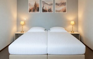 A double bed with two bedside tables, each with a lamp, in a room with light blue walls and three framed pictures above the bed. - Stunning home in Vlagtwedde with sauna (Vlagtwedde)