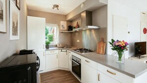 A modern kitchen with white cabinets, a stove, oven, and a microwave. - Stunning home in Vlagtwedde with sauna (Vlagtwedde)