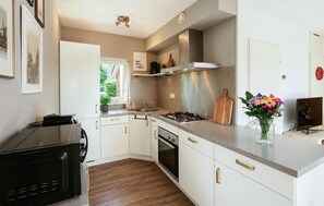 A modern kitchen with white cabinets, a stove, oven, and a microwave.