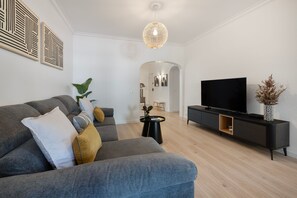 Ett modernt vardagsrum med en grå soffa, en svart TV-möbel och en stor platt-TV.