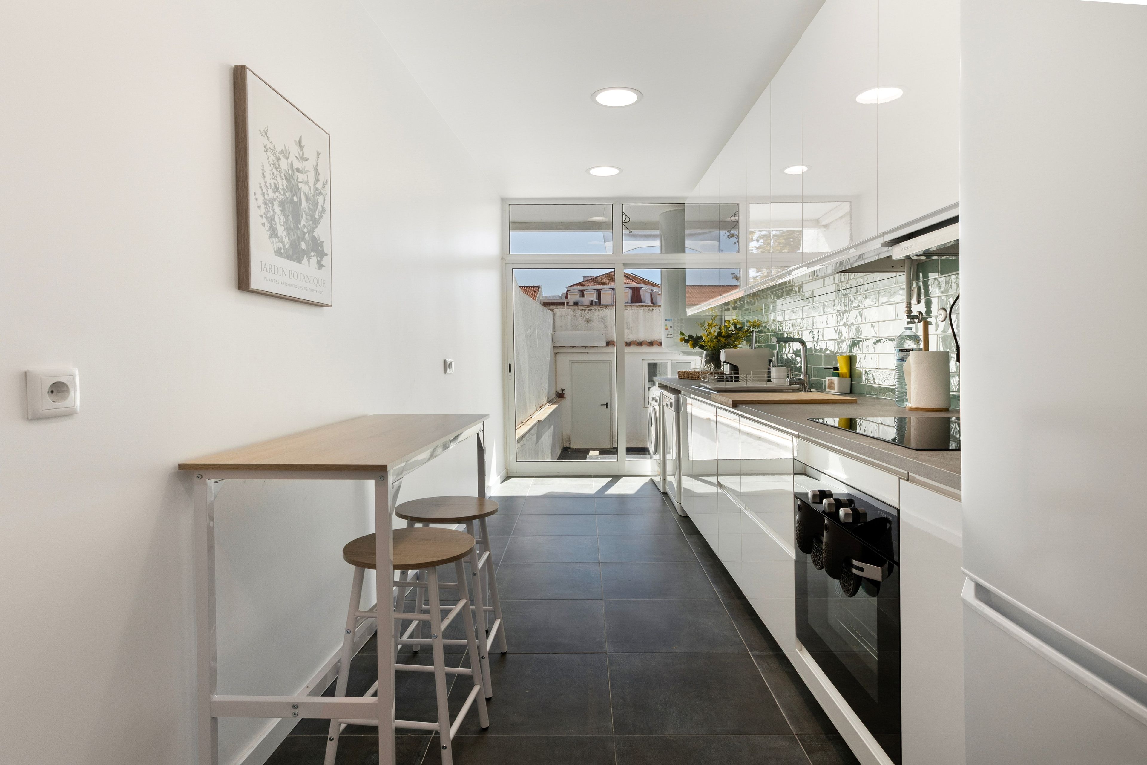 A modern kitchen with a central island, a built-in oven, and a view through the glass door.