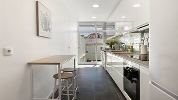 A modern kitchen with a central island, a built-in oven, and a view through the glass door.