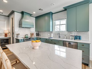 A modern kitchen with teal cabinets, a marble island, and stainless steel appliances. - Carlton Landing-La Dolce Vita (Carlton Landing)