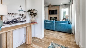 Ein modernes Wohnzimmer mit einem blauen Sofa, einem Holztischchen und einem großen gerahmten Kunstwerk.