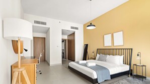 Un dormitorio moderno con una cama, mesitas de noche, un escritorio y una lámpara.