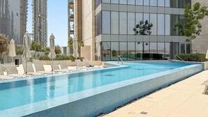 Un edificio moderno con piscina, sillones y sombrillas.