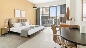 Habitación de hotel con cama, escritorio, silla, ventana grande con vistas e iluminación en el techo.