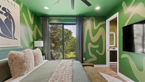 Une chambre à coucher avec un lit, un ventilateur de plafond, une télévision et une vue sur l’extérieur.