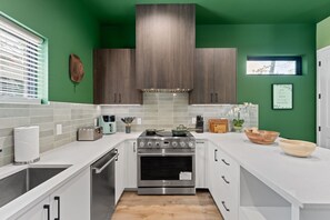Een moderne keuken met witte aanrechtbladen, een roestvrijstalen oven en donkere houten keukenkastjes.