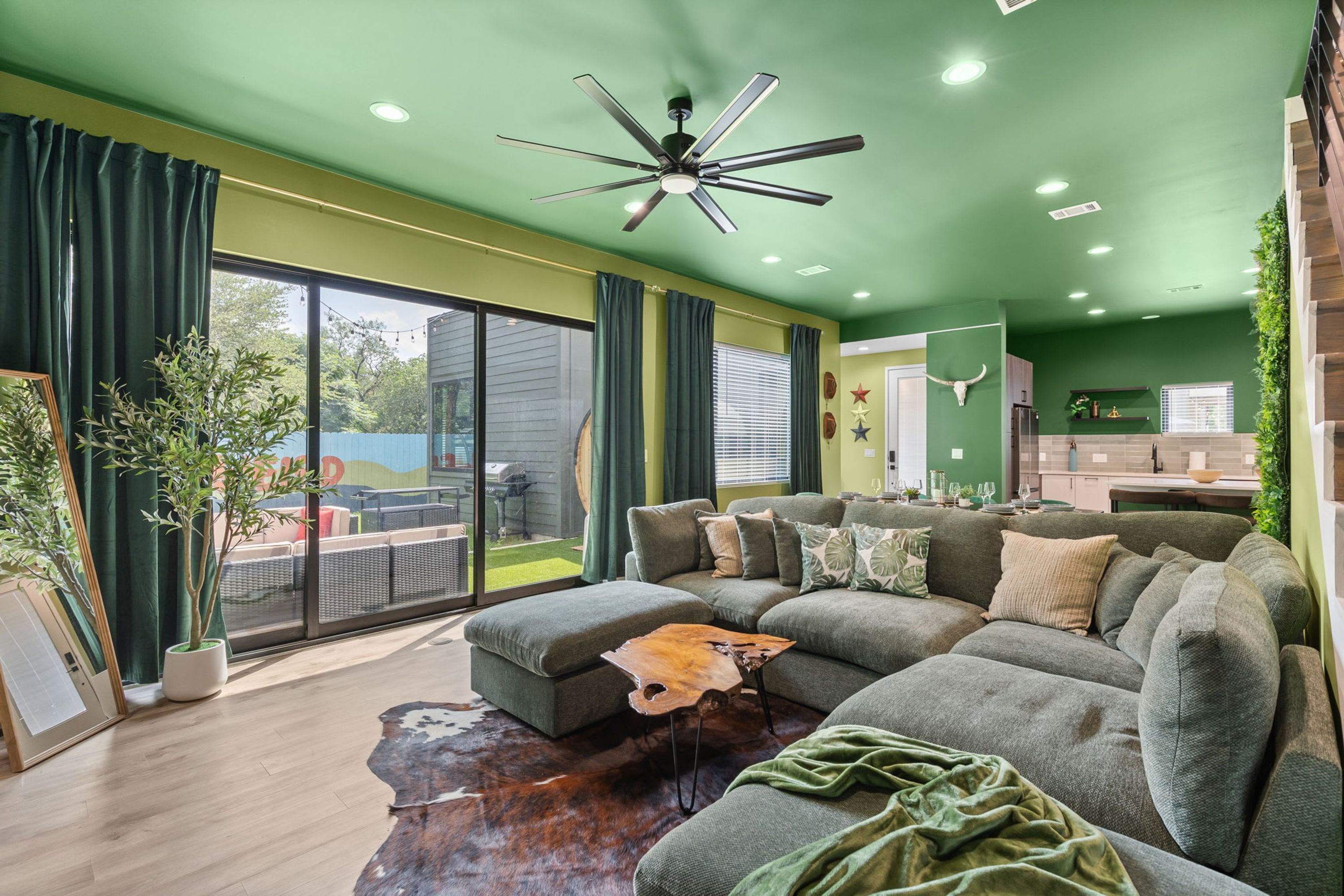 A modern living room with a sectional sofa, a ceiling fan, and a view of the backyard.