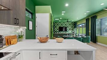 A modern kitchen with a white island, wooden cabinets, and a green accent wall.