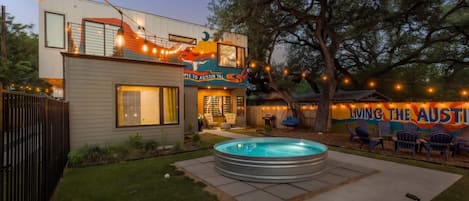 A modern house with a swimming pool, outdoor seating, and string lights.