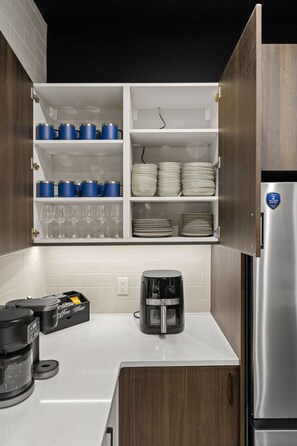 Una cocina con gabinetes blancos, un refrigerador de acero inoxidable y una cafetera sobre la encimera.