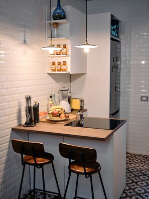 A kitchen with a central island, two bar stools, hanging pendant lights, and a refrigerator. - w Charming Apartment in Milan (Milan)