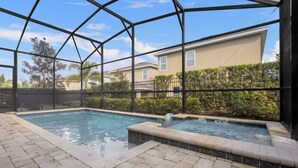 Área de piscina ao ar livre com compartimento de vidro, duas banheiras de hidromassagem e vista para um prédio residencial.