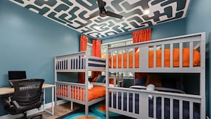 Um quarto com beliches, uma escrivaninha e um computador.