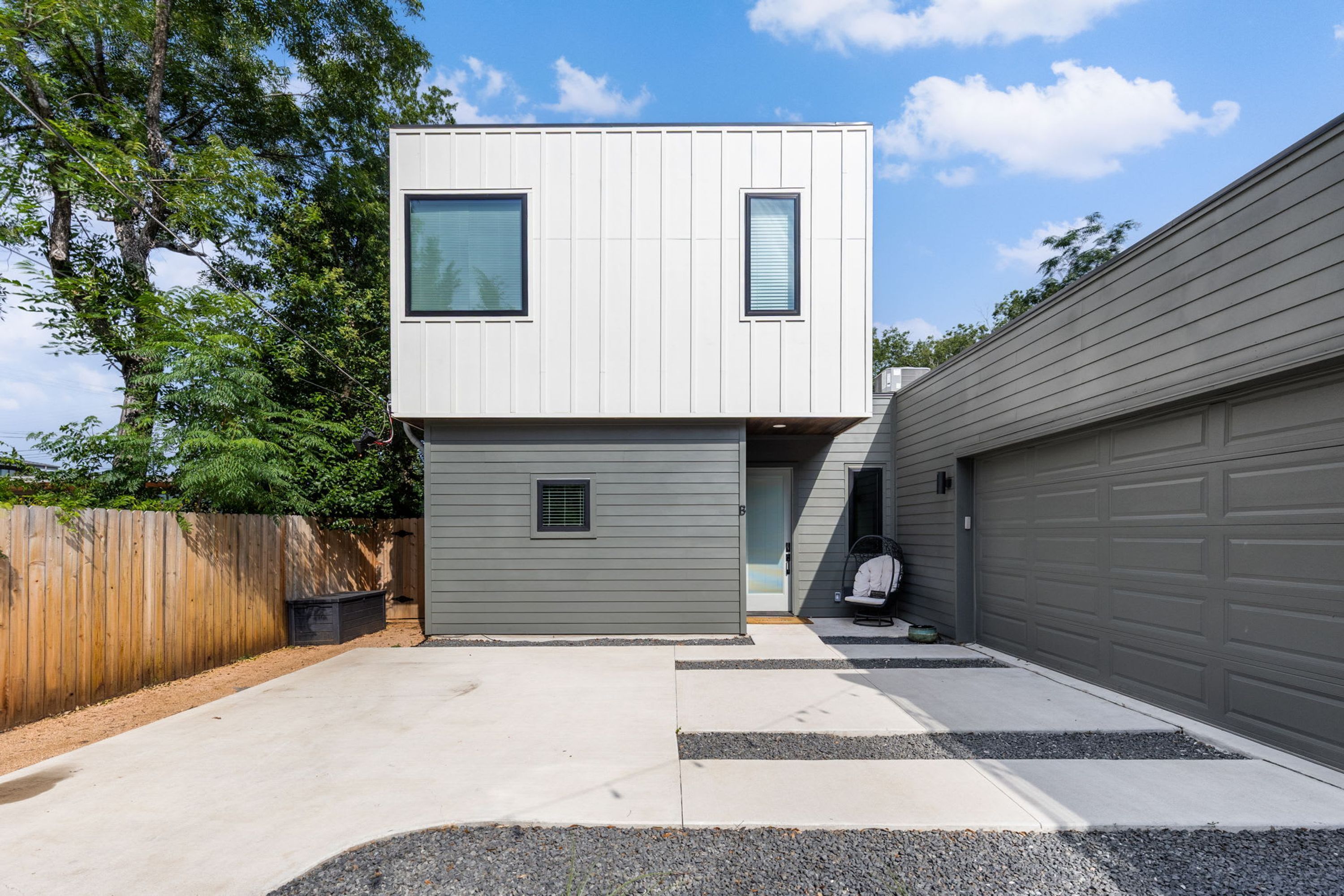 Een modern herenhuis met garage, overdekte entree en een klein terras.