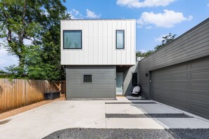 Een modern herenhuis met garage, overdekte entree en een klein terras.