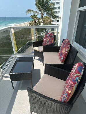 A balcony with wicker furniture, a glass table, and a view of the ocean. - 2-bedroom condo in awesome Fort Lauderdale with AC and gym access (Fort Lauderdale)