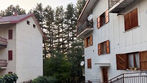 Un edificio di due piani con un balcone, un'antenna parabolica e persiane di legno.