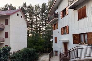 Ein zweistöckiges Gebäude mit Balkon, Satellitenschüssel und Holzläden.