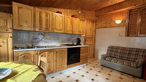Una cucina con mobili in legno, un tavolo da pranzo con una tovaglia gialla e un divano a quadri.