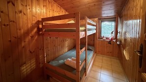 Una camera in una baita di legno con letti a castello, una finestra vista panoramica e una lampada a soffitto.