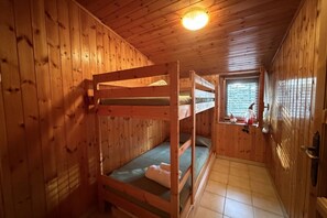 Ein Zimmer in einer Holzhütte mit Etagenbetten, einem Fenster mit Blick und einer Deckenleuchte.